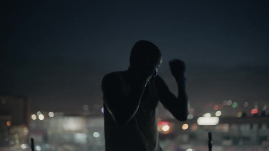 A boxer punches the air on a building rooftop