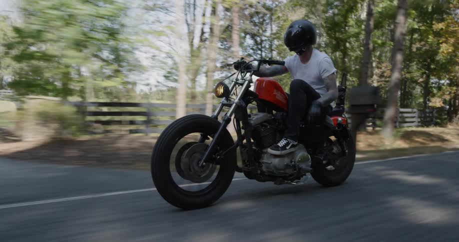 Man is riding motorcycle on highway surrounded by trees