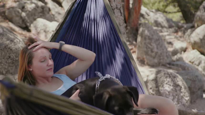 Woman and dog in a hammock overlooking mountains in afternoon