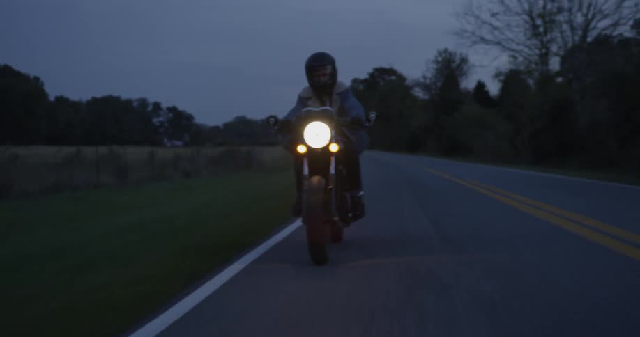 Man rides motorcycle down highway at night