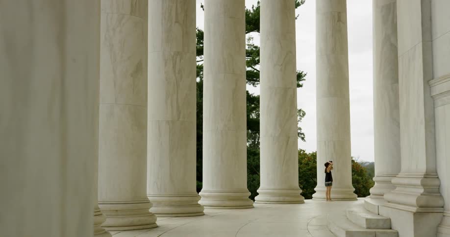 Woman stands next to the tall white pillars