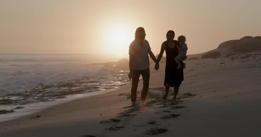 Couple with child walk along beach
