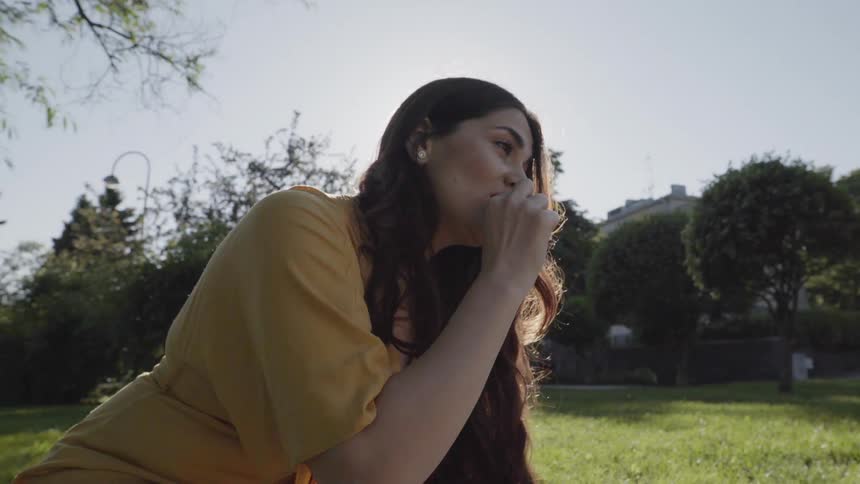 Woman sits on grass eating snack