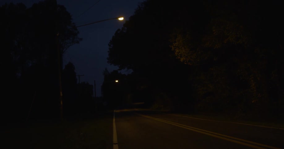 Street lamps shine down on a street at night