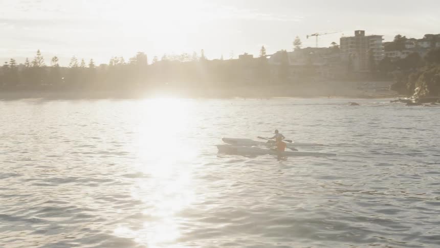 Two men are kayaking on the ocean in the afternoon
