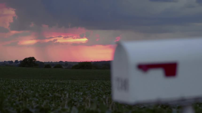 A mailbox sits on a farm at sunset