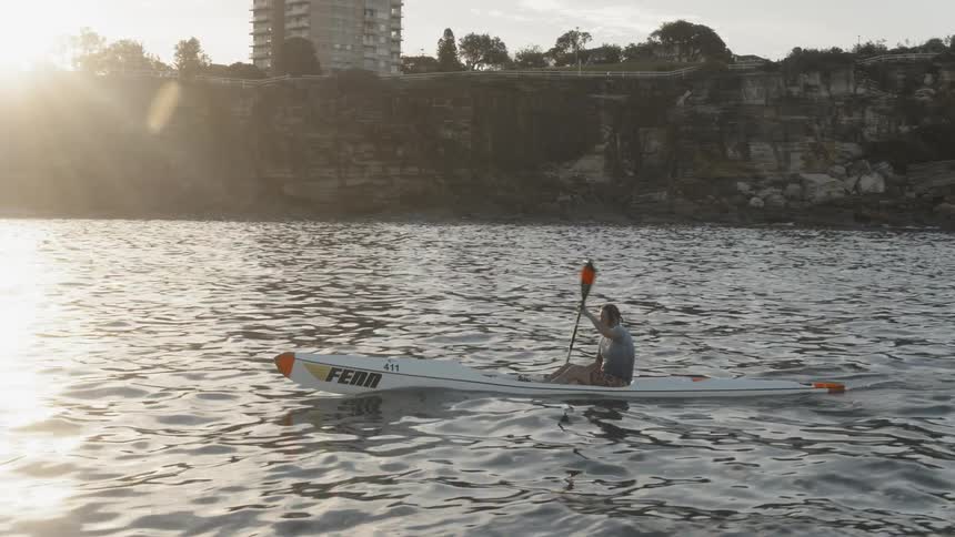 Man kayaks just off the coast at sunset