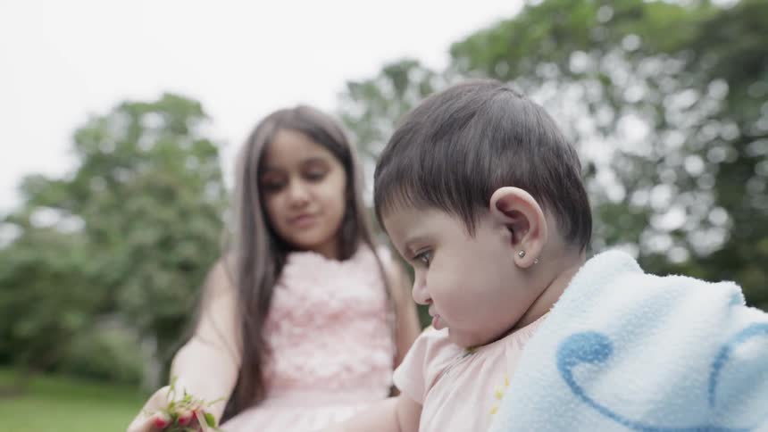 A girl and baby play on a lawn