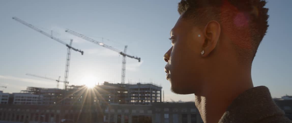 A man stands in a city at sunset