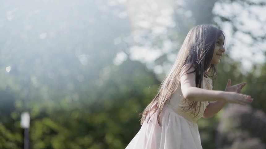 A girl spins on a grassy lawn