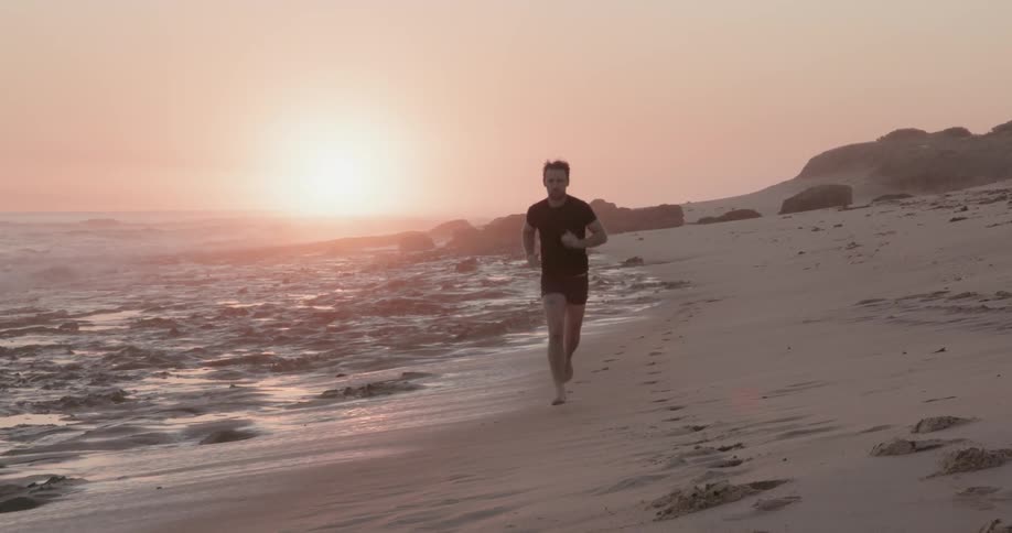 Man is jogging on beach at sunset