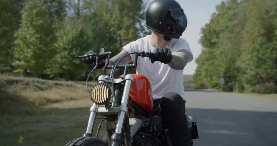 Man takes off on motorcycle on road on sunny day