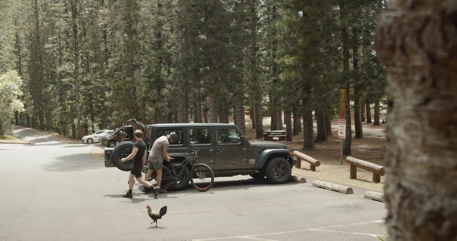 Man gets out of a jeep while another man inspects his bike