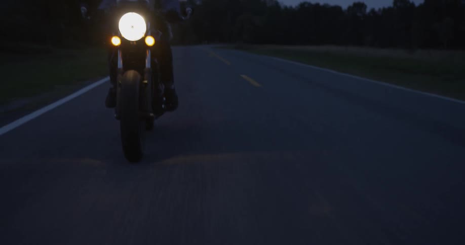 Man rides a motorcycle down a highway at night