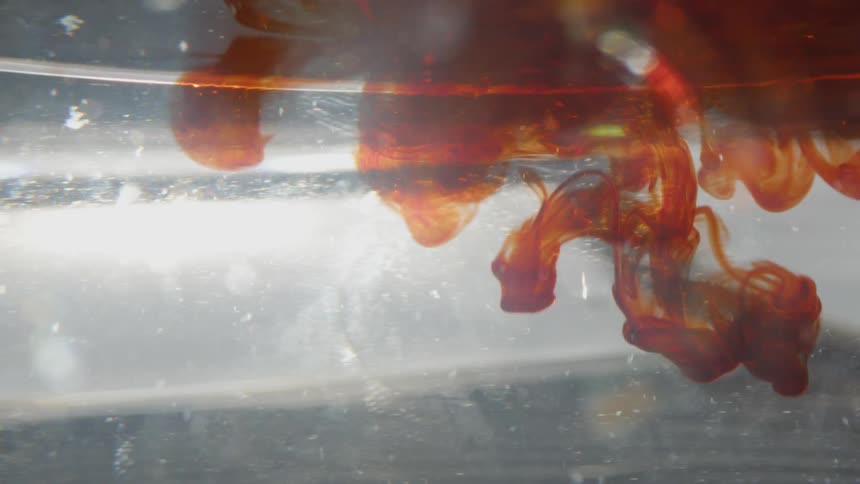 Red liquid spreads in the water