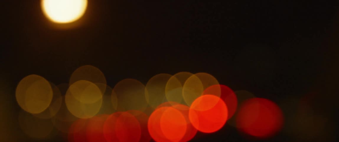 Traffic lights blur then come into focus at night