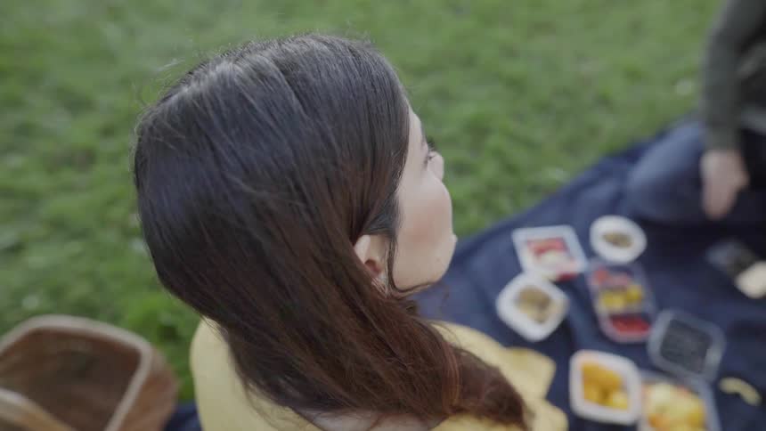 A man and woman are talking as they picnic outside in a park