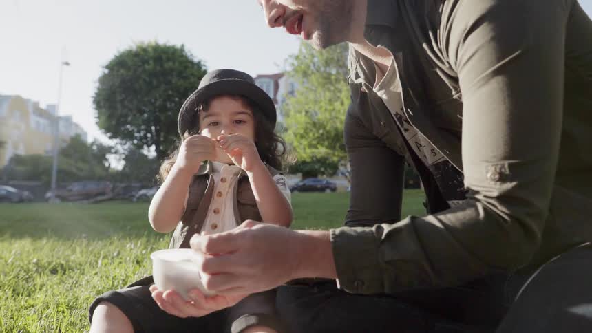 Man talks to a child while taking an object out of a small white bowl