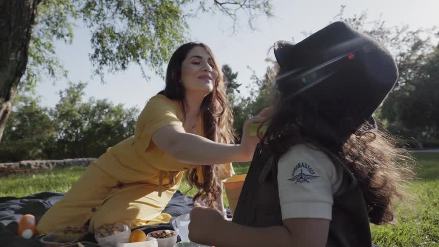 Woman wipes a child's face while having a picnic on a sunny day