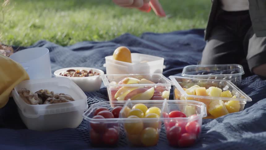 An assortment of fresh fruit and snacks spread on a picnic blanket.