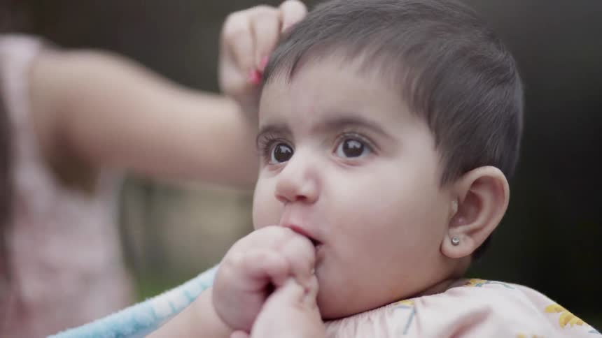 A girl rubs a baby's head