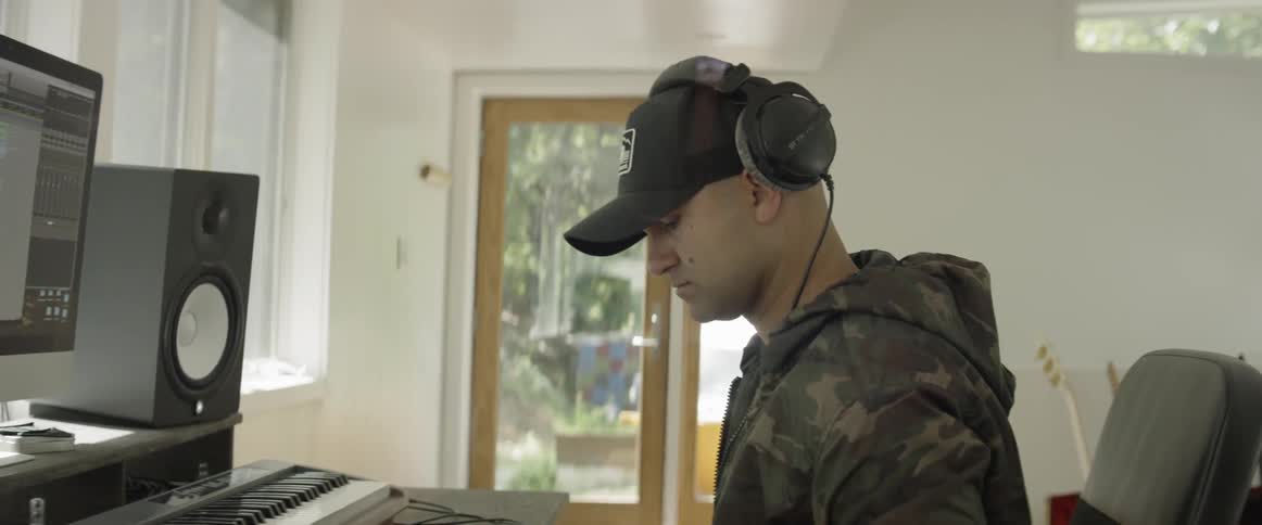A man plays a keyboard in a music studio