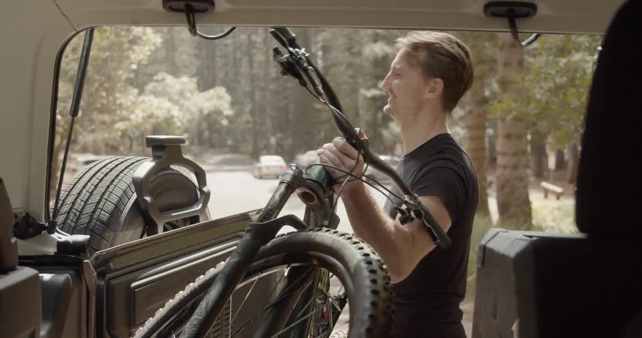 A man pulls a bike out of a truck