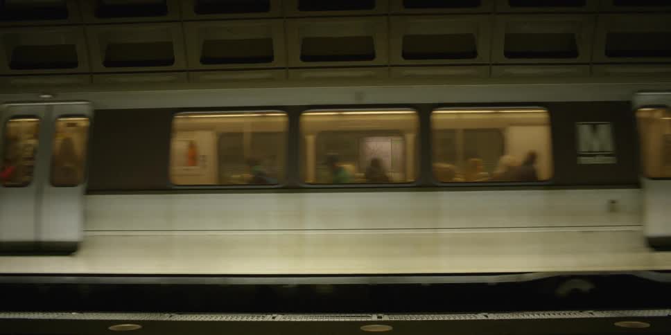 Train drives into a subway station at night and slows to a stop