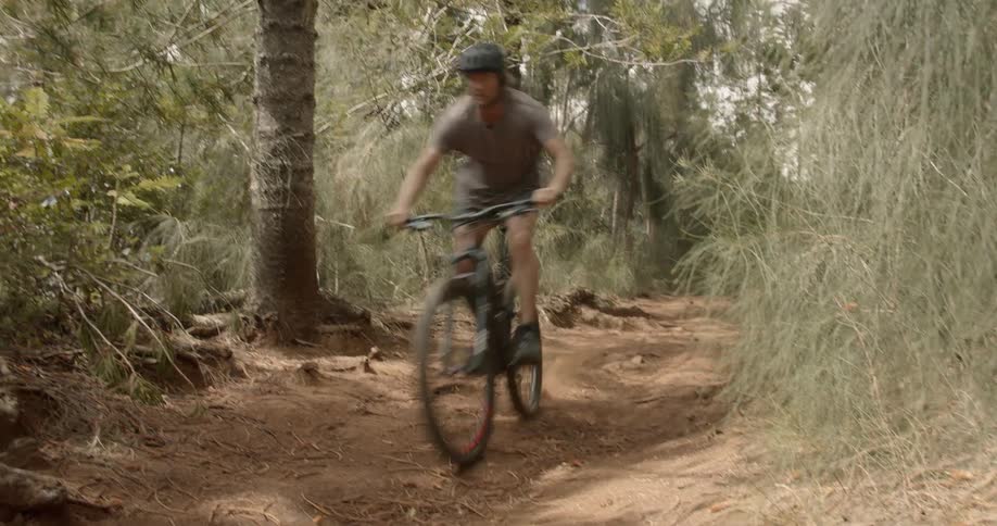 Man rides a bike down a dirt path in the woods