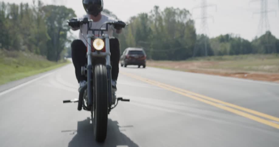 A motorcyclist rides on a rural road