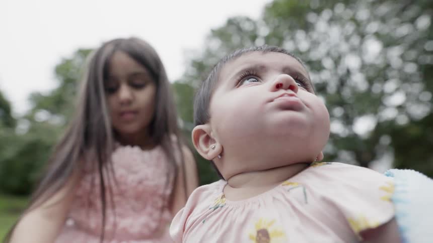 A girl and baby play on a lawn