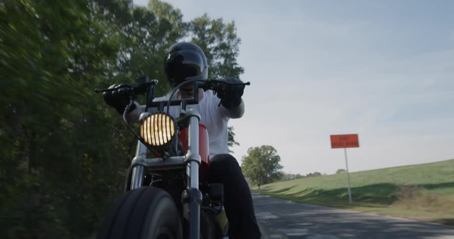 A motorcyclist rides on a rural road