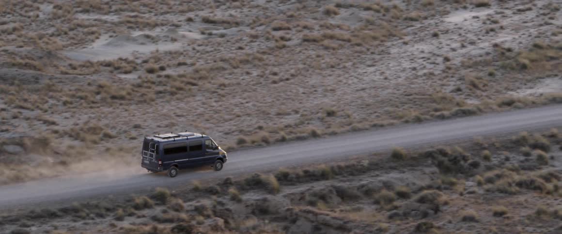 a mercedes bus drives trough the desert
