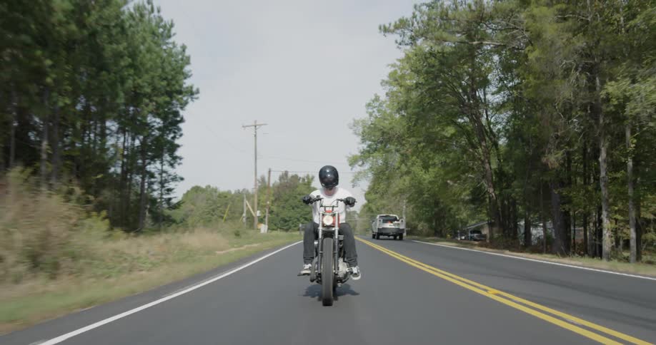A man motorcycles on a rural road