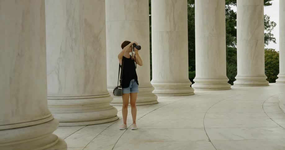 Woman takes a photograph near large pillars