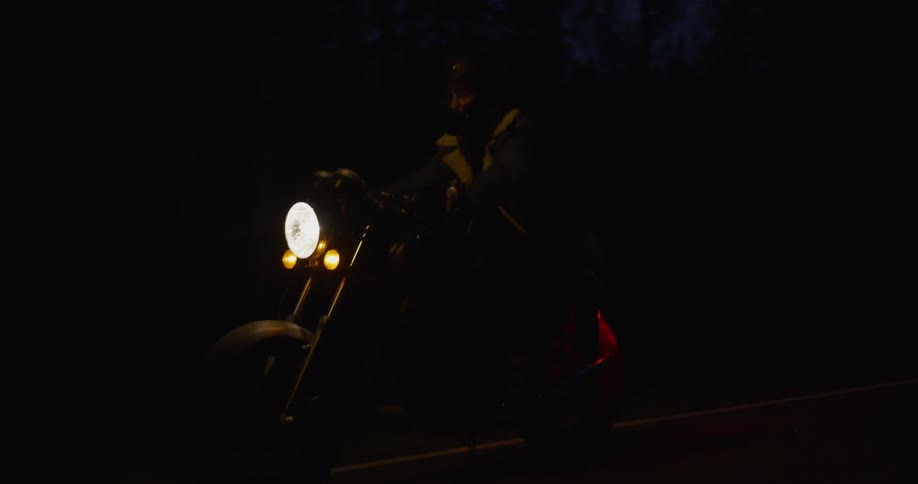 A motorcyclist rides in the dark
