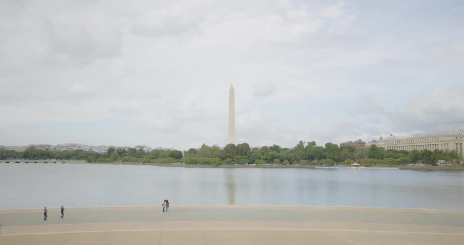 People walk by water in Washington DC near Washington Monument