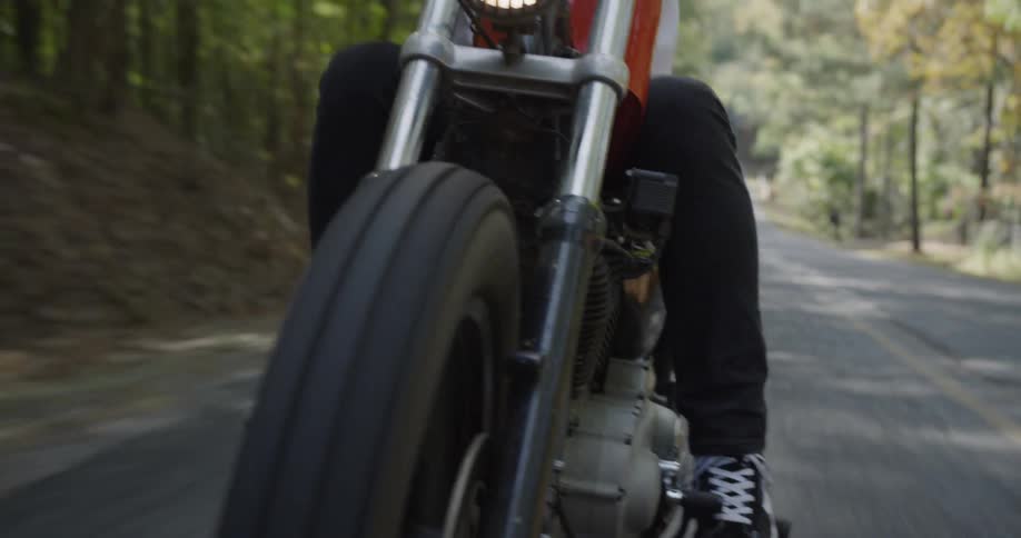 A man is riding a motorcycle on a rural road in daylight