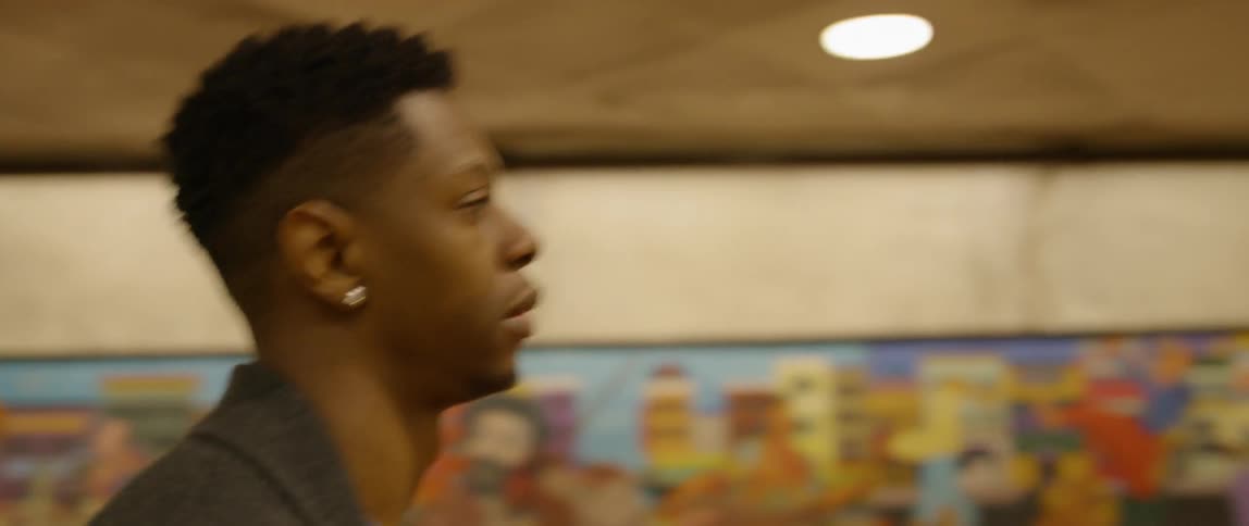 A man is walking past a mural in a subway station