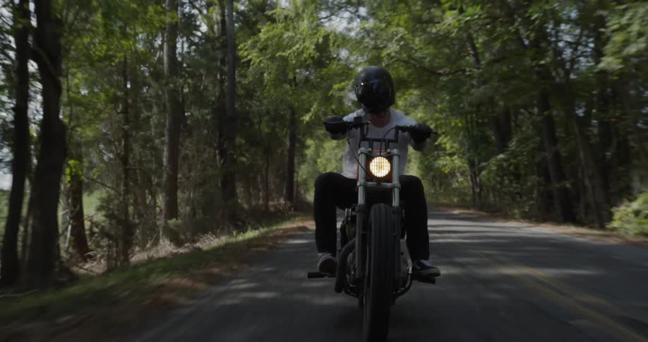 Man is riding motorcycle on highway surrounded by trees