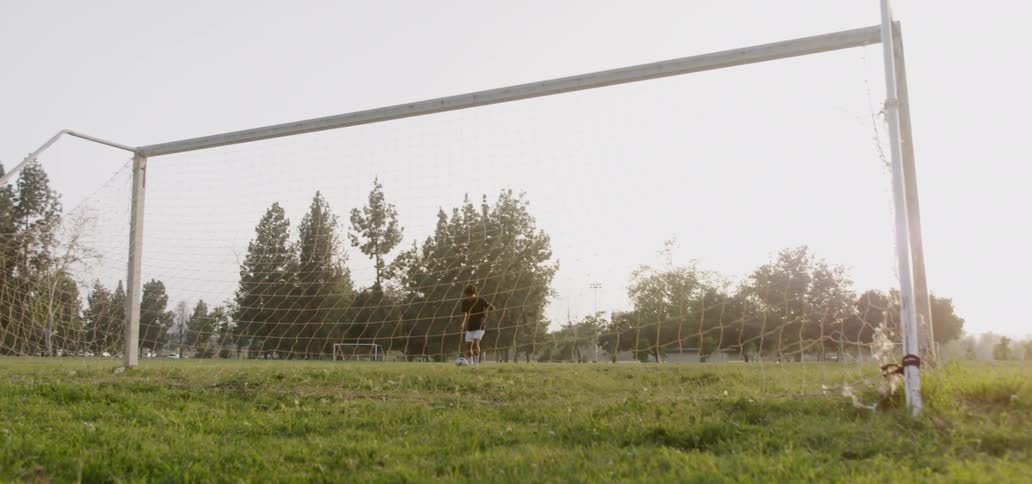 Boy kicks soccer ball into goal