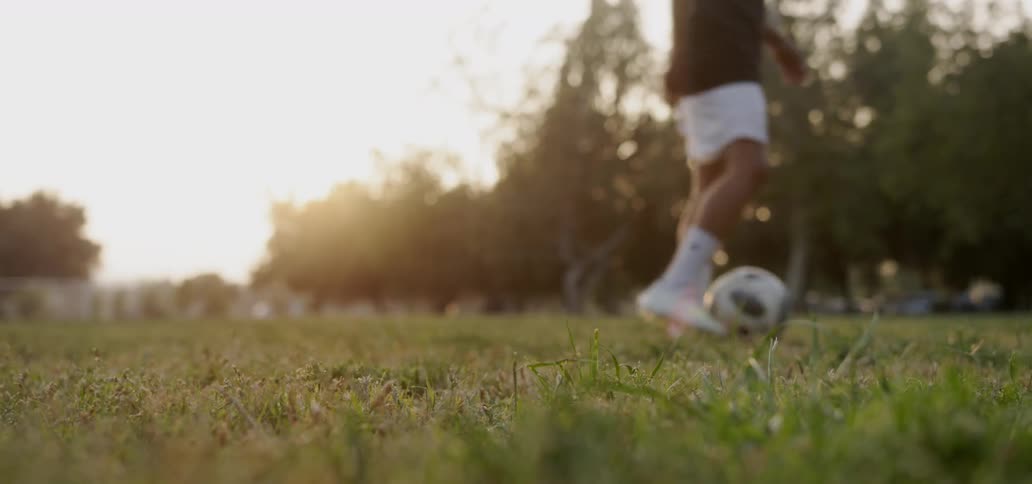 Man kicks a soccer ball in a field
