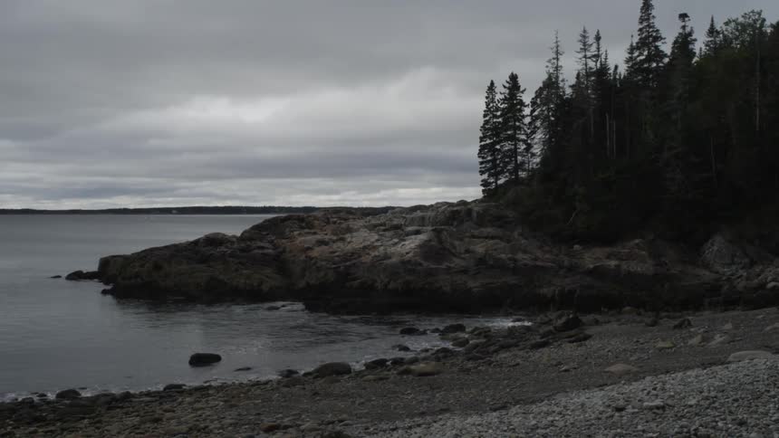Standing on the shore looking across rocks at the ocean on an overcast day