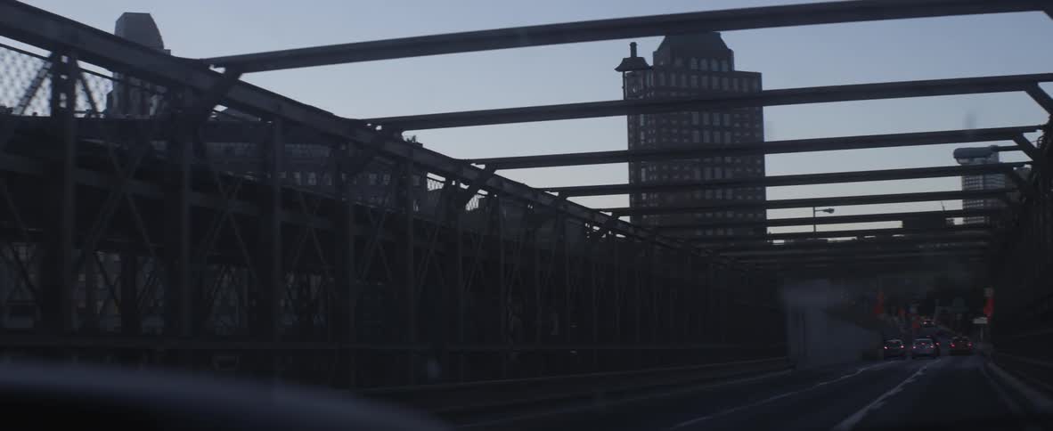 Car driving across a city bridge under metal beams