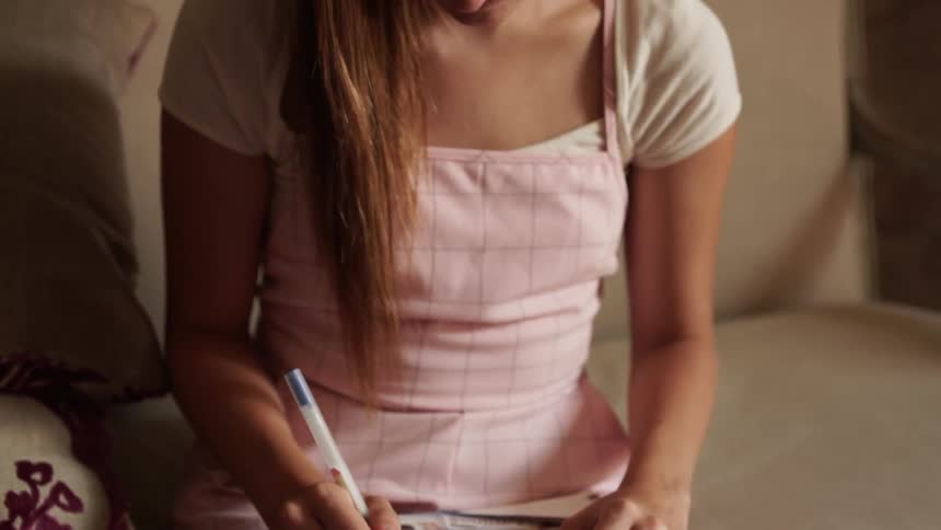 Woman writes in a notebook as she sits on the floor
