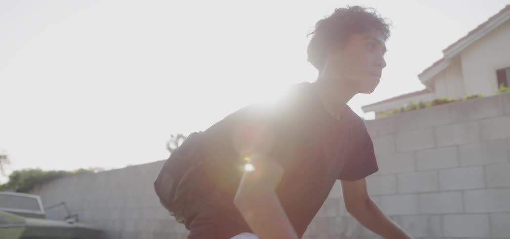 A teenager bicycles with a backpack on a sunny day