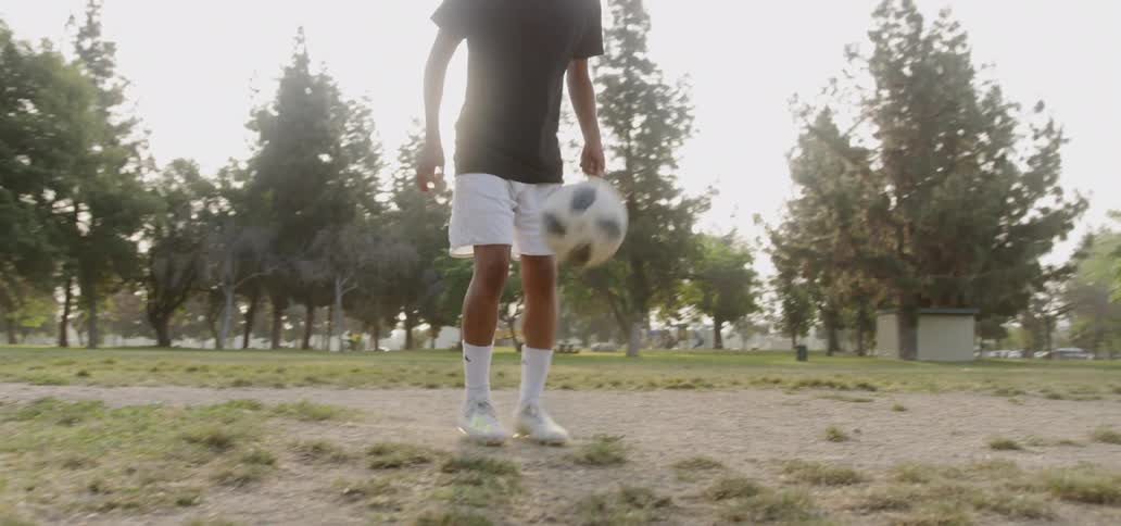 A teenager plays soccer in a field