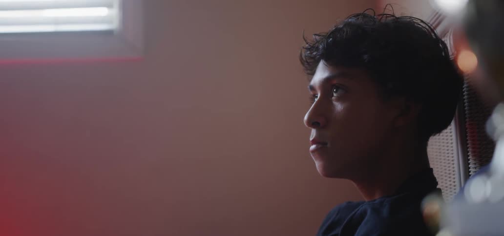 Boy looks around then rises from his bed
