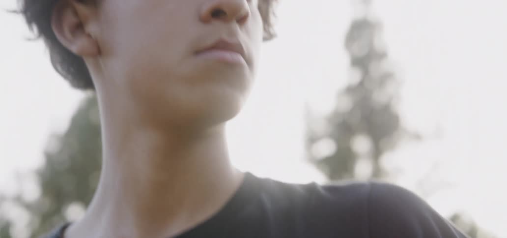 Teenager holds a soccer ball outside on a sunny day