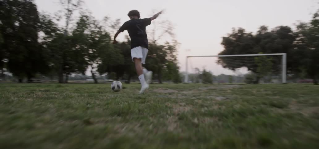 Boy kicks soccer ball into goal post